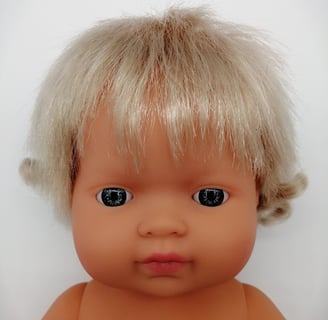 a Miniland baby doll with blonde hair and blue eyes