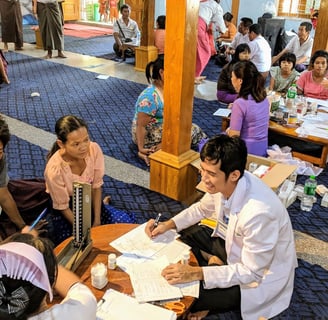Doctor Zaw surrounded by patients sitting and counselling them in a smile