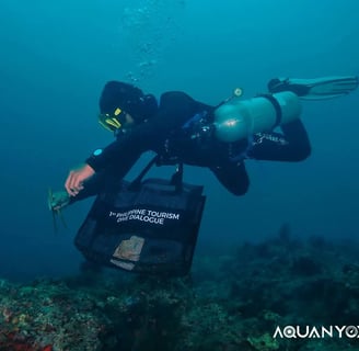 Scuba diver Chu Taga Isla outdoors picking up trash with tourism bag