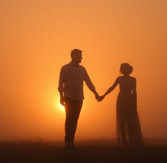 a man and woman holding hands in front of a sunset