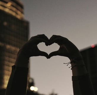 hands forming a heart in front of a building