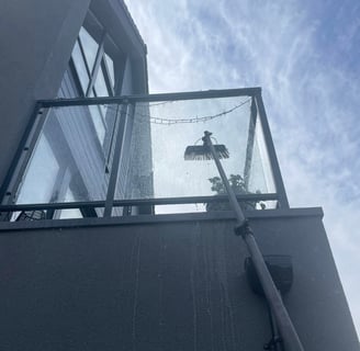 outdoor cleaning services Fife - exterior glass balcony being cleaned with an extendable brush