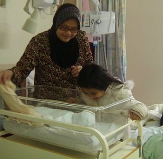 Doula Jannah with her 3rd born baby and her first born baby looking on to the baby. All ready to be 