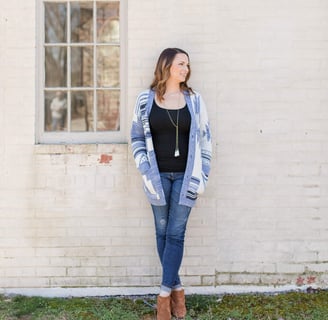 Hana Maren Godfrey standing in front of a white brick wall