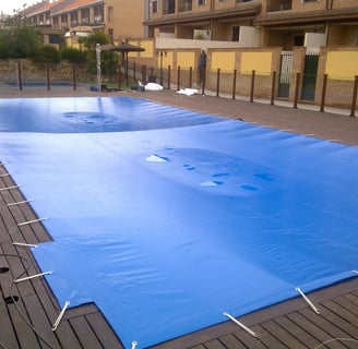 a pool with a blue cover and a tennis court