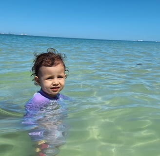 a young girl in a purple swimsuit in the ocean