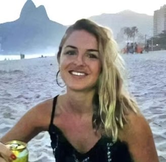 a woman in a black dress sitting at a beach