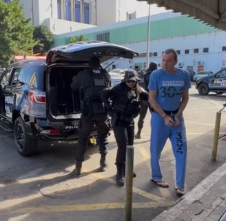 a man in a blue shirt is standing in front of a police car