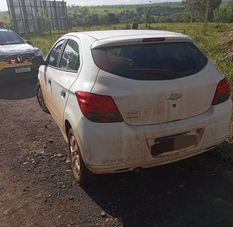 a car parked on a dirt road with a police car behind it carro da vitima