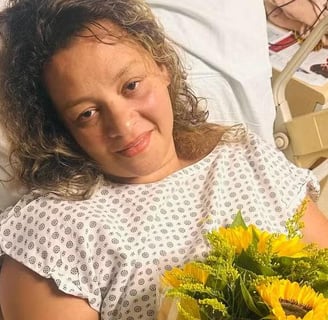 a woman in a hospital bed with a bouquet of sunflowers