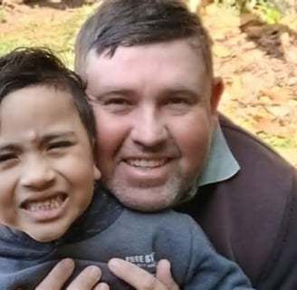 a man and a boy are smiling and hugging