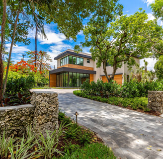 brick driveway leading to a vibrant front yard of a custom built luxury home