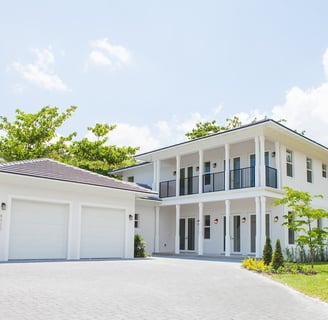 a white luxury home with a large driveway shown and a two door garage