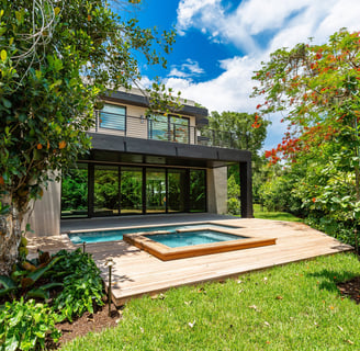 a medium sized luxury home backyard showing vibrant foliage, swimming pool with hot tub and deck