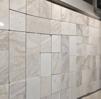 A textured surface made up of numerous small, rectangular wooden tiles. The tiles exhibit a weathered appearance with variations in color from gray to dark brown. Scattered dried leaves and debris rest on the surface, adding a natural element to the composition.