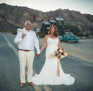 a man and woman holding hands and walking down a road