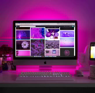A stylish desk setup with a computer displaying a gallery of images, highlighting web design inspiration.