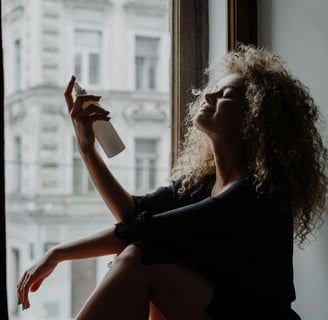 Woman spritzing facial mist by the window — embracing calm and natural skincare ritual