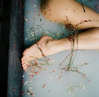 Bare legs in a bath with floating flowers and herbs