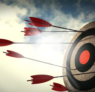 Cork bullseye target with red arrows and cloudy sky background