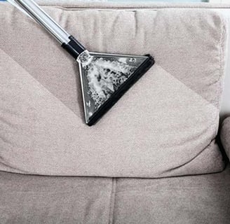 Um sofa sendo aspirado por uma maquina de limpeza de sofa