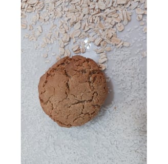 One Only Oats Rolled Oats flavor gluten-free cookie with loose rolled oats in the background.
