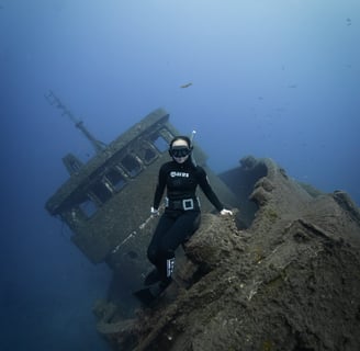 a freediver posing over a wreck ship. Photo taken by Sébastien Saintignan