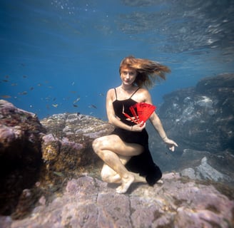 Underwater model posing on a rock with a fan. Photo by taken Sébastien Saintignan.