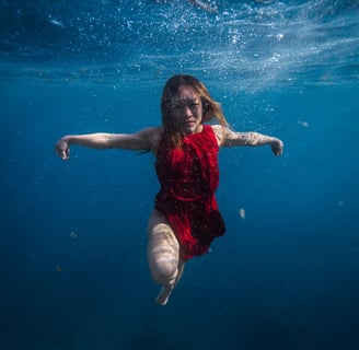 Model in red dress dancing underwater. Photo taken by Sébastien Saintignan