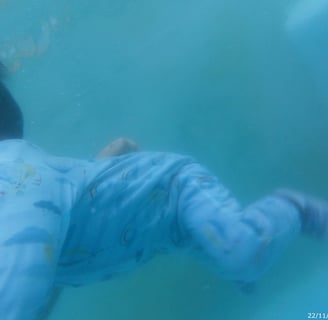 a baby in a blue suit is swimming in the water
