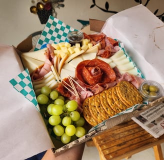 tabla de carnes frías y quesos de finca narvarte con uvas, galletas y aceitunas