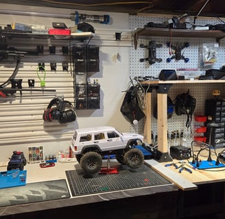 White RC truck on a workbench with tools and bin on pegboard.