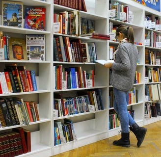 Menina na biblioteca pesquisando sobre faculdades com curso gratuito