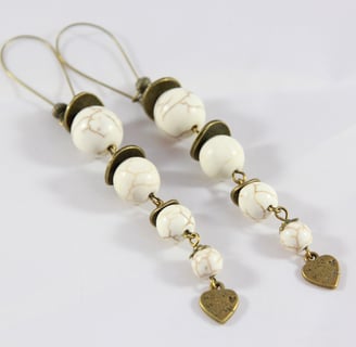 a pair of earrings with white marbled beads