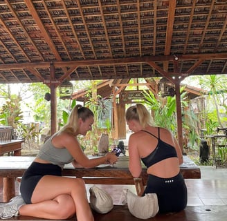 two women sitting on a bench in a wooden table