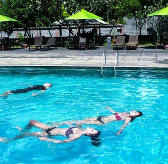 a woman swimming in a pool with two people for intro dive in bali