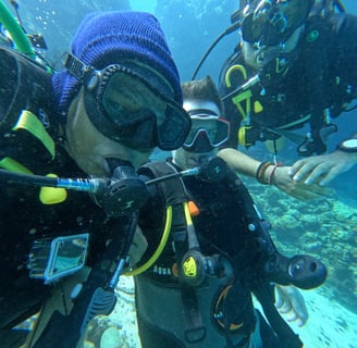 Content creator couple snorkeling with GoPro surrounded by colorful coral reef at Menjangan Island, Bali