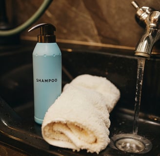 Cat shampoo and a soft towel placed beside a sink ready for grooming.