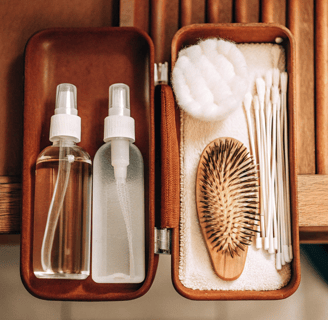 Pet-safe saline solution, cotton pads, and ear cleaning solution placed beside a cat grooming brush.