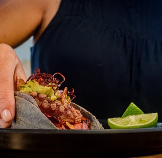 a person holding a taco in a plate by Drai Cabello in Cancun