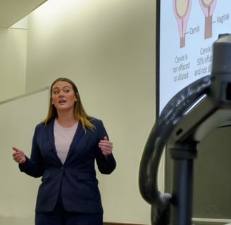 A woman with long hair in a blue suit presenting a pitch