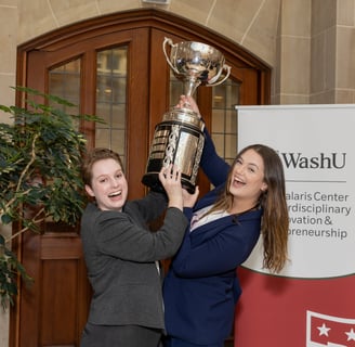 Two women in suits lift a trophy above their heads
