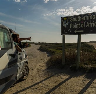 man in car looking at sign to southermost tip of africa