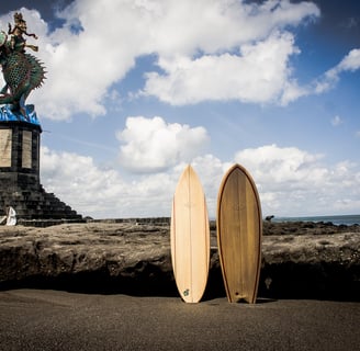 Two handmade balsa surfboards standing on coastal rocks in Bali