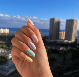 a person's hand with pastel colored manicure with each finger a different color