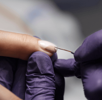 a person in purple glove holding finger doing nails