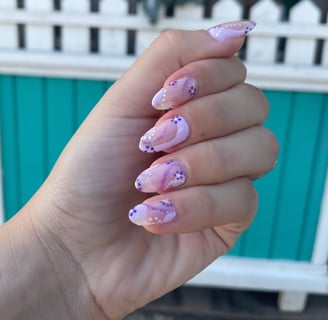 hand in loose fist showing manicure with different shades of purple and floral abstract design