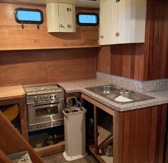 a kitchen with a sink and a gimbled stove, wood walls and sliding cabinet door