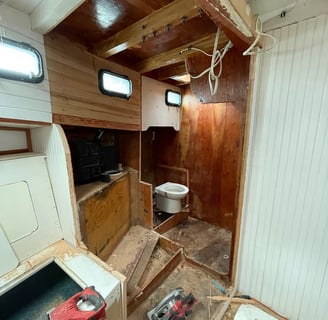 walls to the head (bathroom) cut open with a toilet perched in an unfinished wooden room