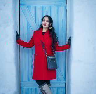 a woman in a red coat and boots standing in front of a blue door